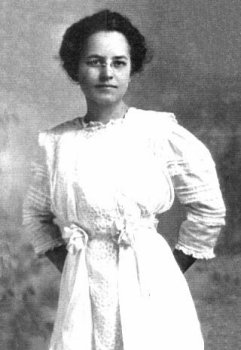 Margaret Young [Stafford], a young woman in a lace trimmed white dress, with white flowers at the waist